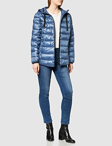 Mujer con chaqueta acolchada azul y jeans.