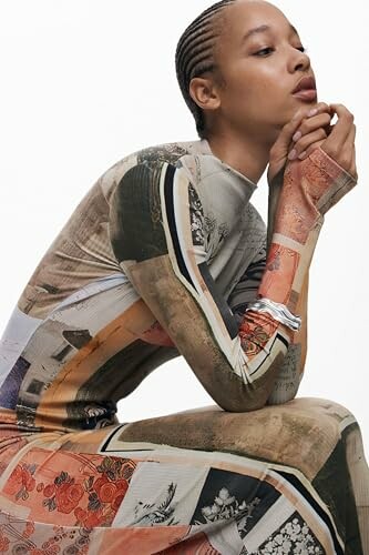 Mujer con vestido moderno y estampado variado, posando pensativa.