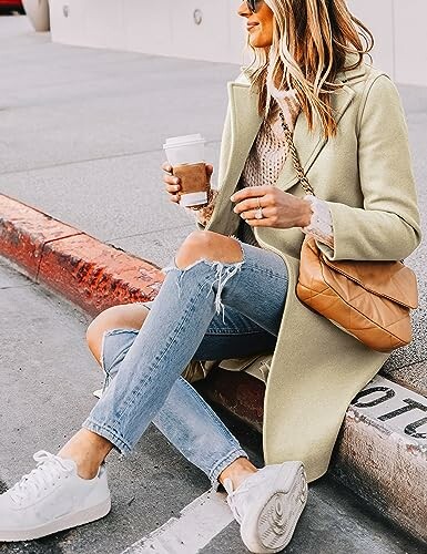 Mujer con abrigo y vaqueros rotos sosteniendo café