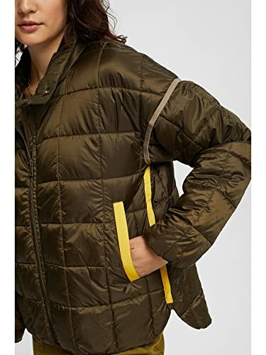 Mujer con chaqueta acolchada verde y detalles amarillos.