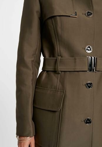 Detalle de un abrigo trench color caqui con botones y cinturón.