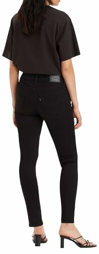 Mujer de espaldas con jeans negros ajustados y camiseta negra.