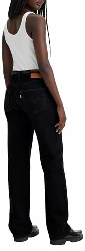 Mujer con jeans negros y camiseta blanca.