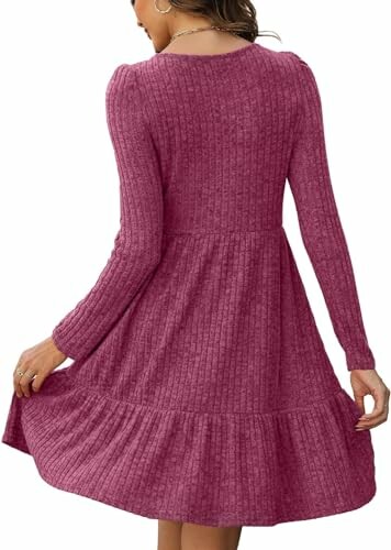 Mujer vistiendo un vestido rosa de punto, vista trasera.