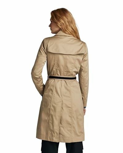 Mujer de espaldas con gabardina beige.