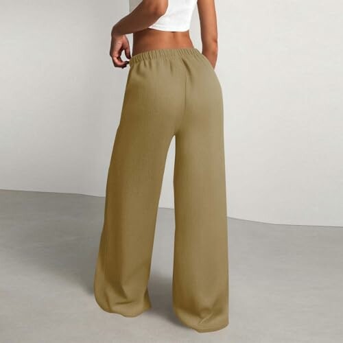 Mujer con pantalones anchos beige de espaldas.