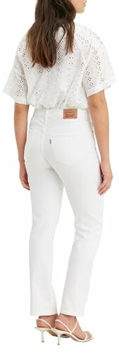 Mujer con blusa y jeans blancos vista desde atrás.